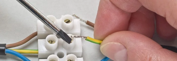 Person verbindet Kabel mit Lüsterklemme und Schraubendreher.